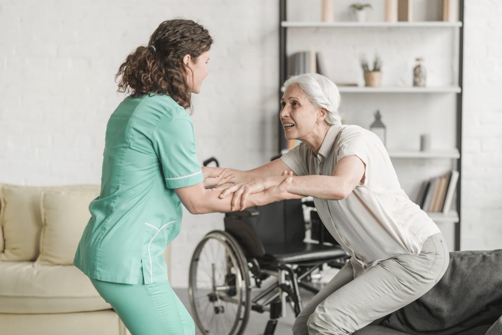 Nurse helping an elderly women patient get up on her feet at patient's home under home healthcare services